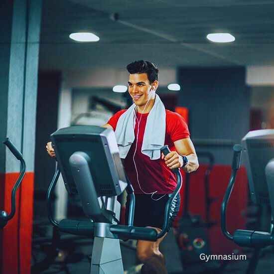 A man smiling on an exercise treadmill at the Godrej Sector 43 Gurgaon project gym.